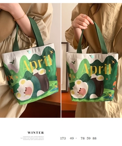 Detail of canvas handbag featuring a cute bear illustration with a green woven handle