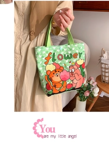 Detail of green canvas tote with cartoon tiger print and blue button closure