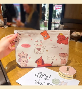 Close-up of cute cartoon dog illustrations on a cream canvas cosmetic storage bag