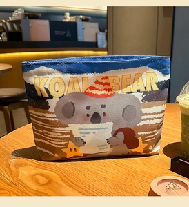 Lifestyle shot of a canvas storage bag with cute koala pattern on a wooden table