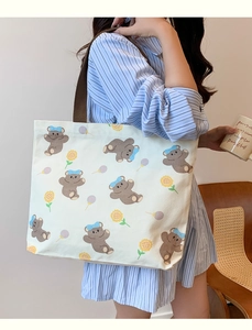 Lifestyle shot of large canvas tote bag with brown bear print and dark handles