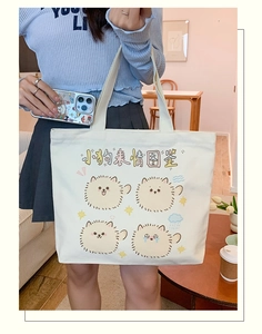 Detail of white canvas tote bag featuring four cute cartoon puppies and sturdy handles