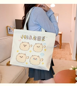Detail view of large canvas tote bag with cute cartoon dogs on an ivory shoulder bag