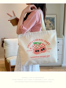 Detail of cute cherry canvas tote bag with shoulder strap shown in a lifestyle scene