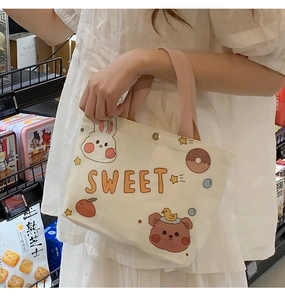 Close-up of off-white canvas bag with cute cartoon prints and pink handles