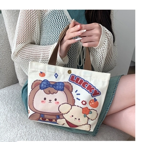 Detail of off-white canvas tote bag with lucky cartoon print and brown handles