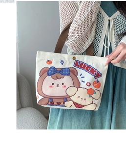 Detail of canvas tote bag with lucky cartoon bear print and secure metal snap closure