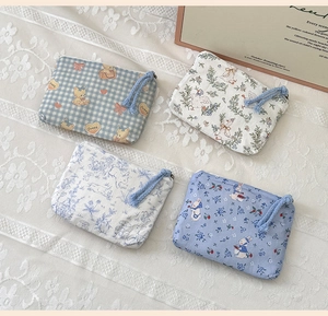 Detail view of four mini cotton coin purses with cute cartoon patterns on lace tablecloth
