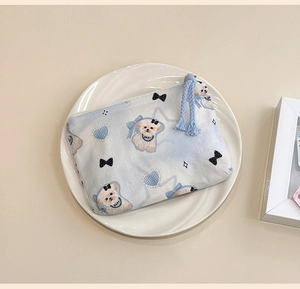 Close-up of cute cartoon cotton mini coin purse with zipper and blue woven tassel detail
