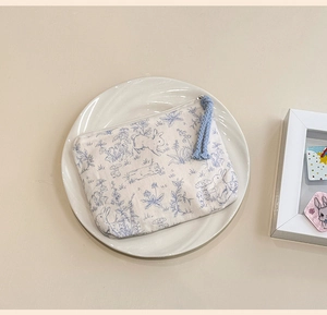 Detailed view of a mini fabric coin purse with blue rabbit prints on white ceramic tray