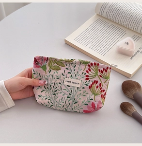 Detail of floral canvas makeup bag with jacquard leaf pattern and metal zipper closure