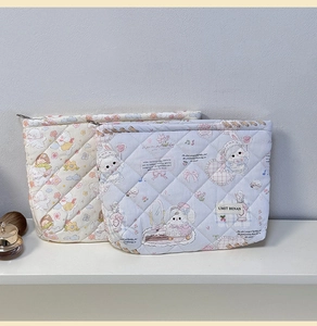 Detail showing the quilted cotton fabric and floral rabbit patterns on the cosmetic bag