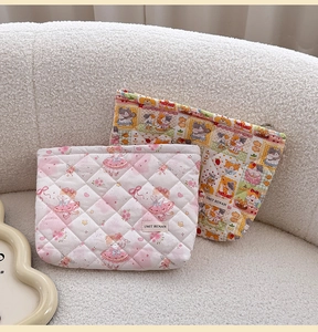 Close-up of quilted cosmetic bags with ballet girl and cat patterns on soft fleece sofa
