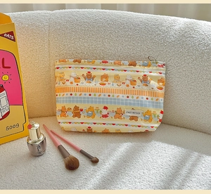 Close-up of cute cartoon bear pattern makeup bag on soft white plush surface