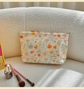Detail of cute floral makeup bag with fairy prints and zipper on a soft white sofa