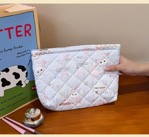 Detailed macro view of the light blue quilted makeup bag with cute rabbit pattern and logo