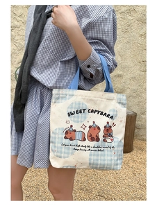 Detailed view of Capybara canvas tote bag with blue handles and cartoon party graphics