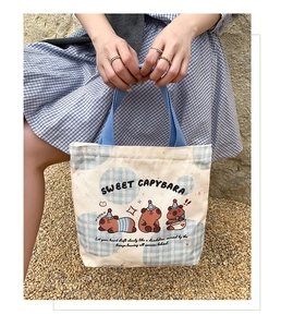 Detail of Capybara canvas tote bag featuring cute cartoon prints and blue handles