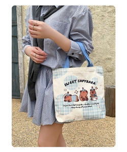 Close-up of Kapybara canvas tote bag with blue handles and cute cartoon capybara print
