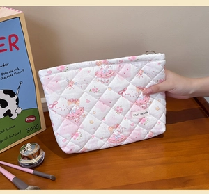 Detailed close-up of quilted floral cosmetic bag with ballerina print and metal zipper