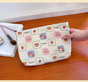 Close-up of canvas makeup bag with cute bear and strawberry cartoon prints and woven label