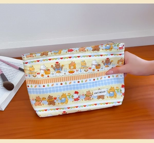 Handheld view of a cute cartoon bear canvas makeup bag with colorful striped patterns