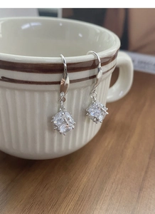 Detail shot of cube drop earrings with cubic zirconia on a ceramic cup edge