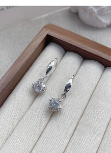 Macro shot of S925 sterling silver cube earrings with sparkling square zircon on wood tray