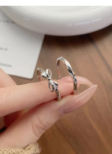 Detailed view of S925 sterling silver bow and mobius couple rings worn on hands