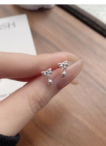 Close-up of S999 sterling silver bow earrings with round beads shown on fingers