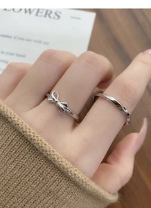 Close-up of S925 silver bow and Mobius twist rings worn together on a finger
