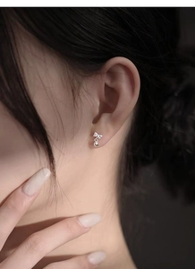 Close-up of elegant S999 sterling silver bow earrings with round bead drop on model