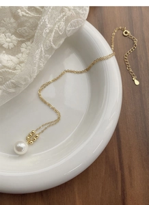 Détail d'un collier de perles en argent S925 sur plat en céramique blanche avec fermoir
