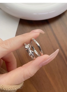 Detailed close-up of S925 sterling silver bow and twisted wave rings for couples