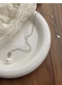 Vue détaillée du pendentif en perle d'argent S925 sur une dentelle blanche délicate