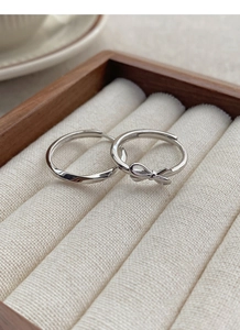 Close-up of S925 sterling silver bow and twisted ribbon rings in a luxury jewelry box
