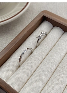 Close-up of S925 sterling silver bow and wave rings inside a premium wooden jewelry box