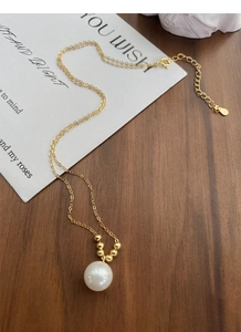 Détail du collier en argent S925 avec perle blanche ronde sur une chaîne dorée