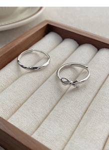 Close-up of S925 sterling silver bow and twisted rope rings in a wooden jewelry box