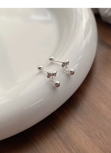 Detailed view of S999 sterling silver bow knot stud earrings on a ceramic dish