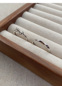 Macro shot of S925 sterling silver bow and wave rings set in a premium wooden jewelry box
