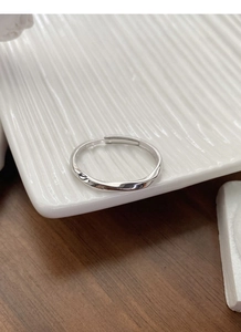 Close-up of S925 sterling silver Mobius twist ring on a white ceramic plate