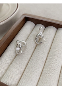 Macro view of polished S925 sterling silver drop U-shaped earrings on a beige display tray