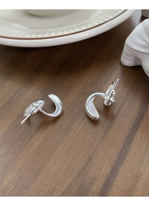 Macro shot of minimalist S925 sterling silver drop U-shaped earrings on wood surface