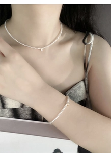 Dettaglio del set collana e bracciale di perle in argento S925 con ciondoli dorati