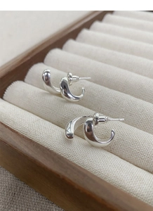 Detail view of U-shaped S925 silver stud earrings on a beige velvet jewelry box tray