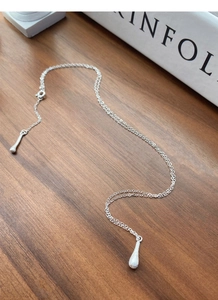 Detail of S925 sterling silver necklace with matte water drop pendant on wood
