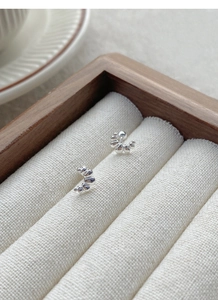 Close-up of S999 sterling silver croissant stud earrings in a wooden jewelry box slot