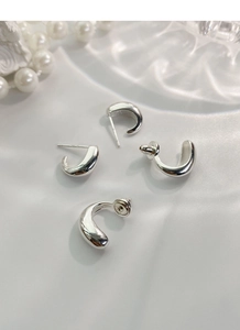 Detail view of polished S925 sterling silver drop U-shaped earrings on white silk fabric