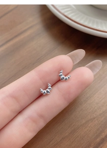 Detailed close-up of S999 silver croissant stud earrings held to show delicate small size